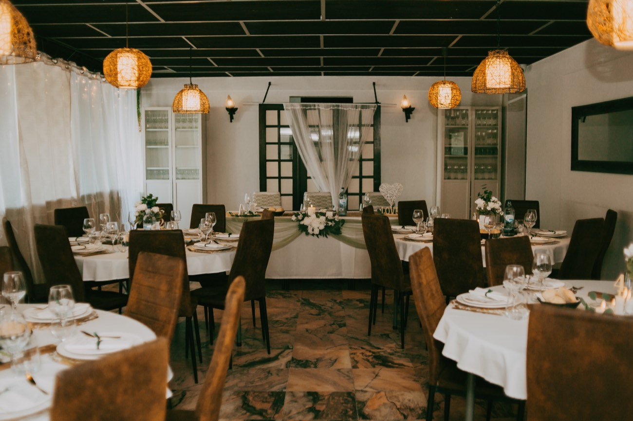 A sala com mesas redondas e a mesa dos noivos ao fundo.